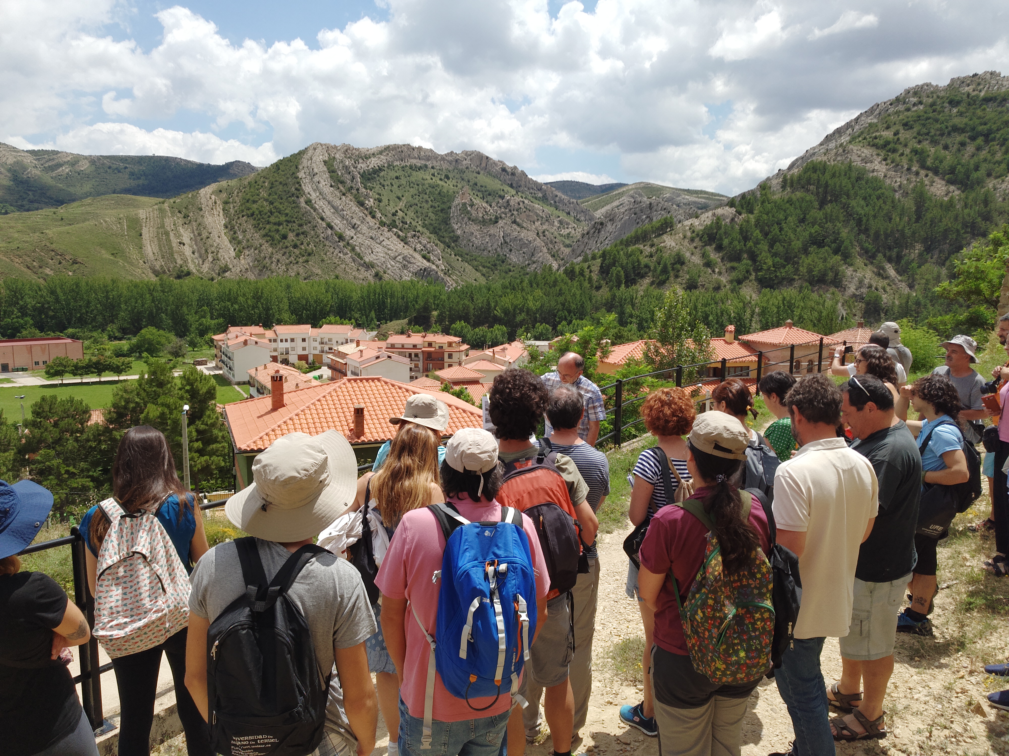 Grupo de estudiantes en el parque geológico de Aliaga.(al fondo, anticlinal de La Olla, emblema y logo del parque)